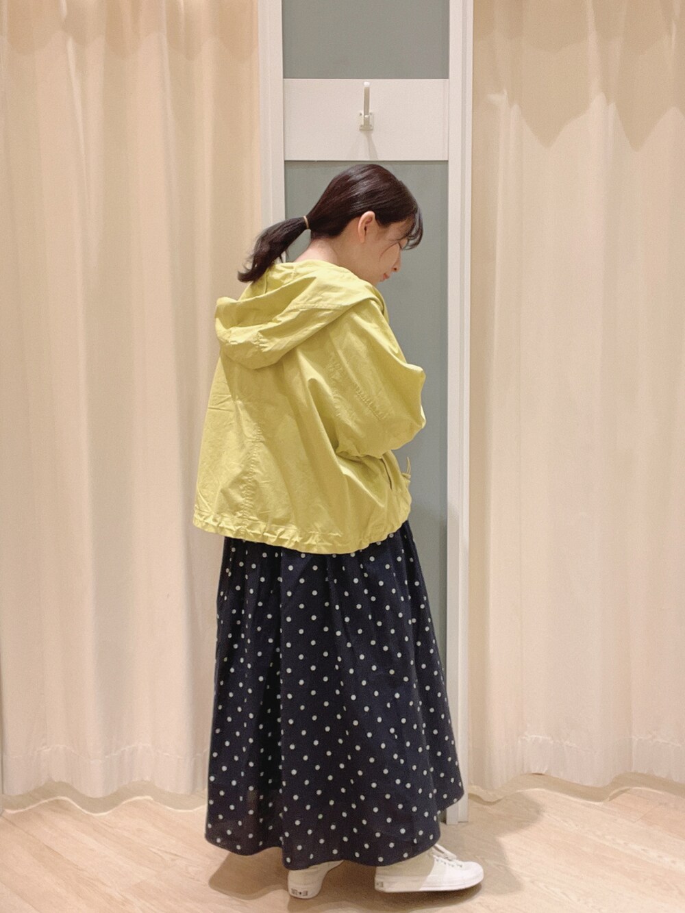 イエロー系のマウンテンパーカー、ホワイト系のTシャツ/カットソー、ホワイト系のスニーカーを着用したレディースの春コーディネートの2枚目の写真