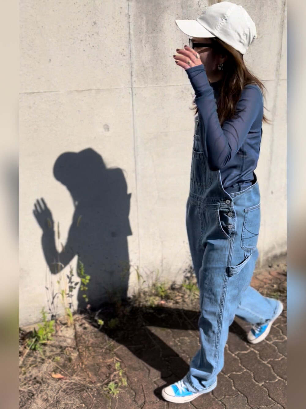 ブルー系のサロペット/オーバーオール、ブルー系のTシャツ/カットソー、ブルー系のスニーカーを着用したレディースの秋コーディネートの3枚目の写真