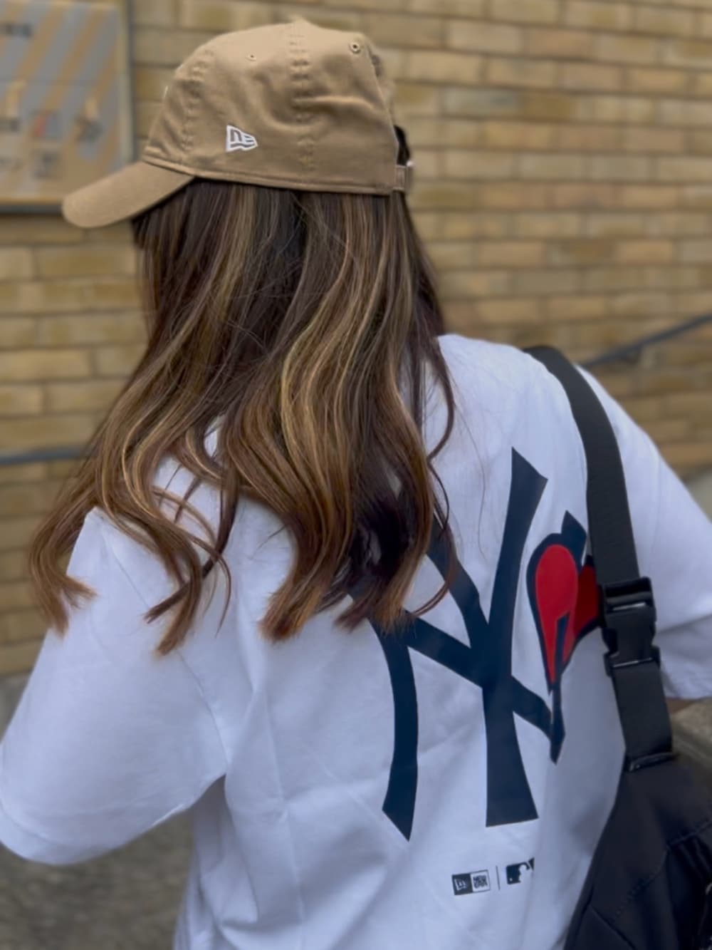 ホワイト系のTシャツ/カットソー、ブラック系のボディバッグ/ウエストポーチ、ブルー系のデニムパンツを着用したレディースの夏コーディネートの5枚目の写真