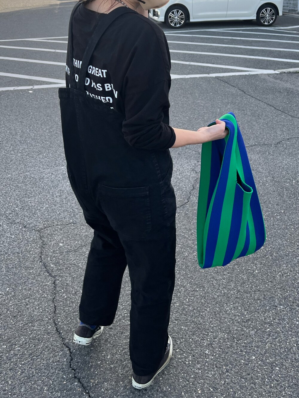 ブラック系のTシャツ/カットソー、ブルー系のトートバッグ、ブラック系のサロペット/オーバーオールを着用したレディースの春コーディネートの2枚目の写真