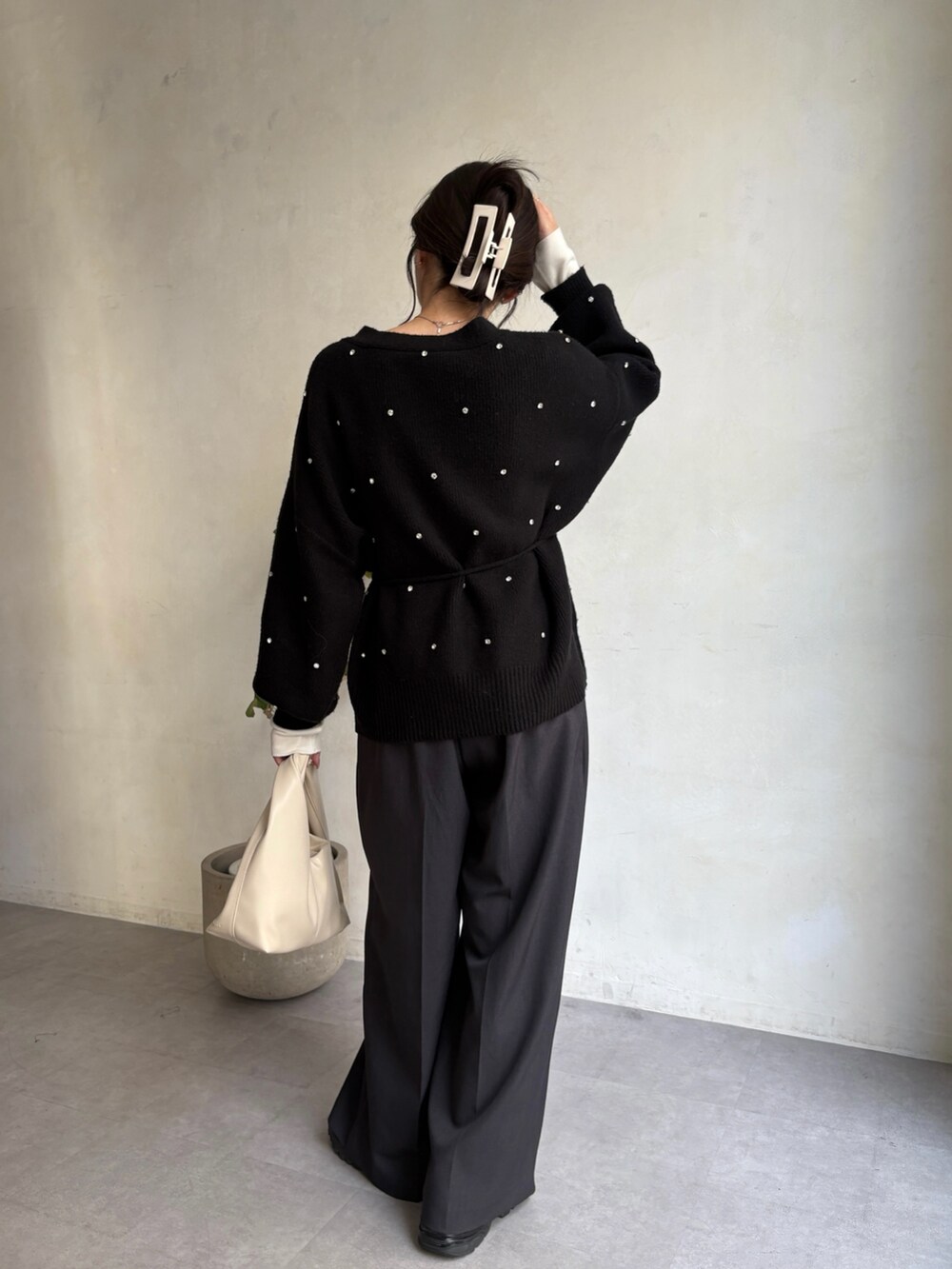 ブラック系のカーディガン/ボレロ、ホワイト系のニット/セーター、ホワイト系のショルダーバッグを着用したレディースの冬コーディネートの2枚目の写真