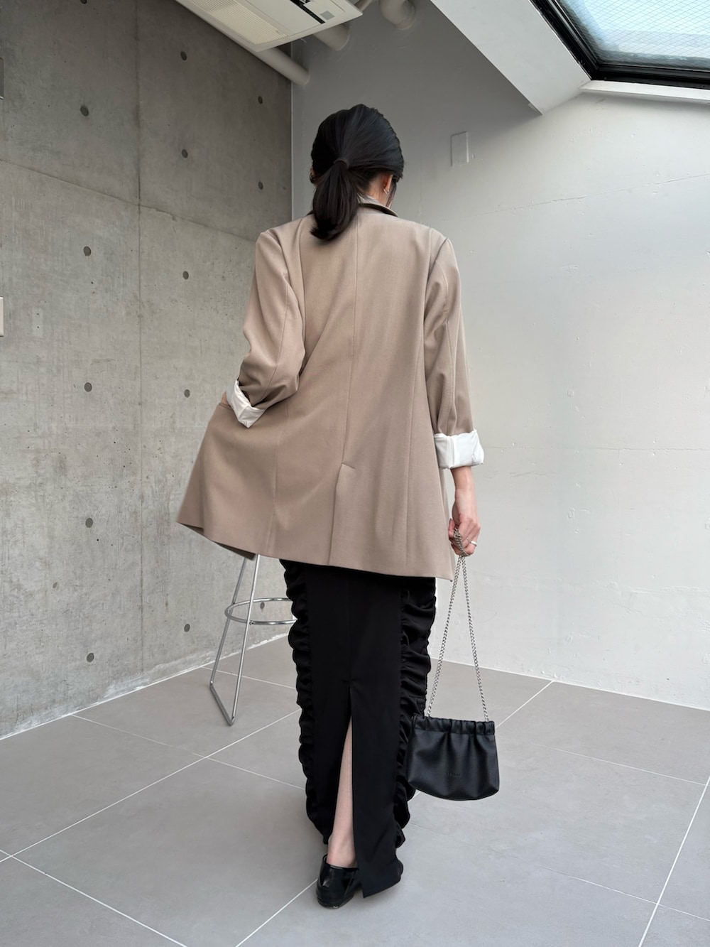 ベージュ系のテーラードジャケット、ブラック系のショルダーバッグ、ブラック系のワンピースを着用したレディースの冬コーディネートの2枚目の写真