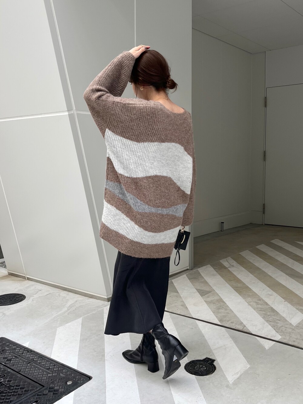 ブラウン系のニット/セーター、ブラック系のショルダーバッグ、ブラック系のスカートを着用したレディースの冬コーディネートの2枚目の写真