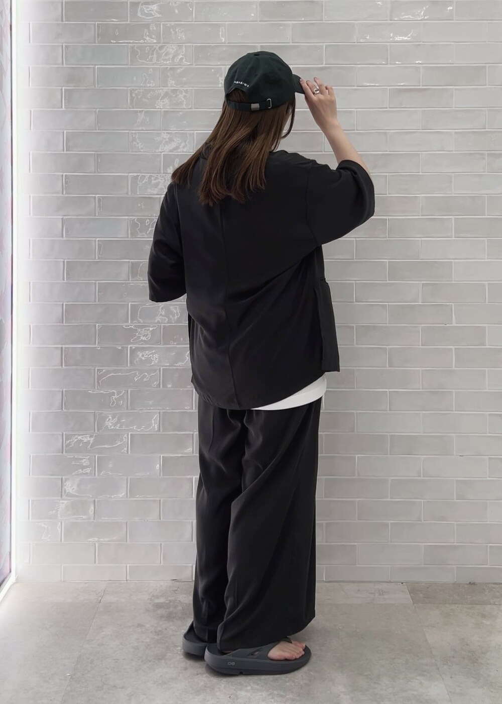 グレー系のサンダル、ホワイト系のTシャツ/カットソー、グレー系のスラックスを着用したレディースの春コーディネートの2枚目の写真