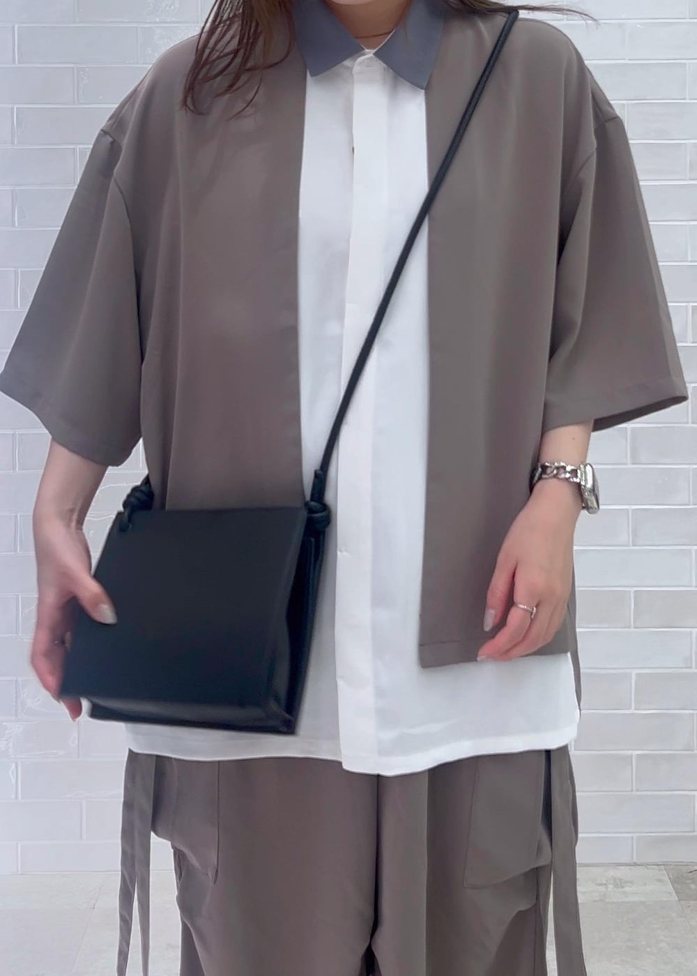 ブラック系のショルダーバッグ、ホワイト系のシャツ/ブラウス、グレー系のカーゴパンツを着用したレディースの夏コーディネートの4枚目の写真