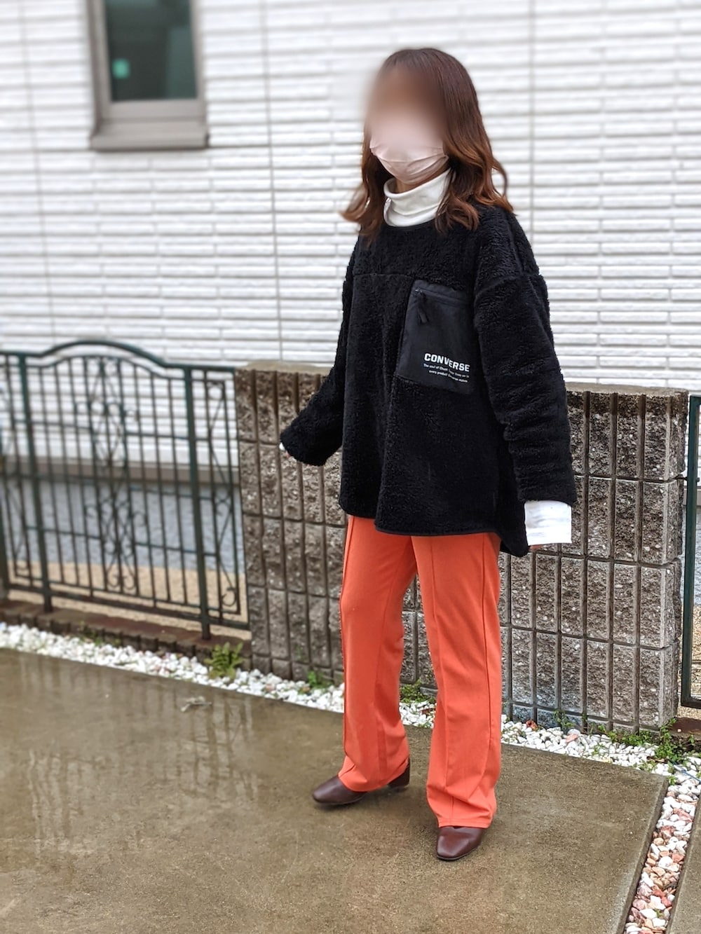 オレンジ系のパンツ、ブラウン系のシューズ、ブラック系のTシャツ/カットソーを着用したレディースの春コーディネートの2枚目の写真