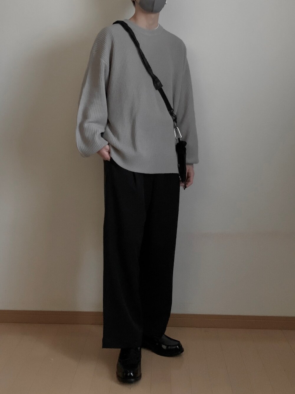 ブラック系のスラックス、グレー系のニット/セーター、ブラック系のボディバッグ/ウエストポーチを着用したメンズの冬コーディネートの2枚目の写真