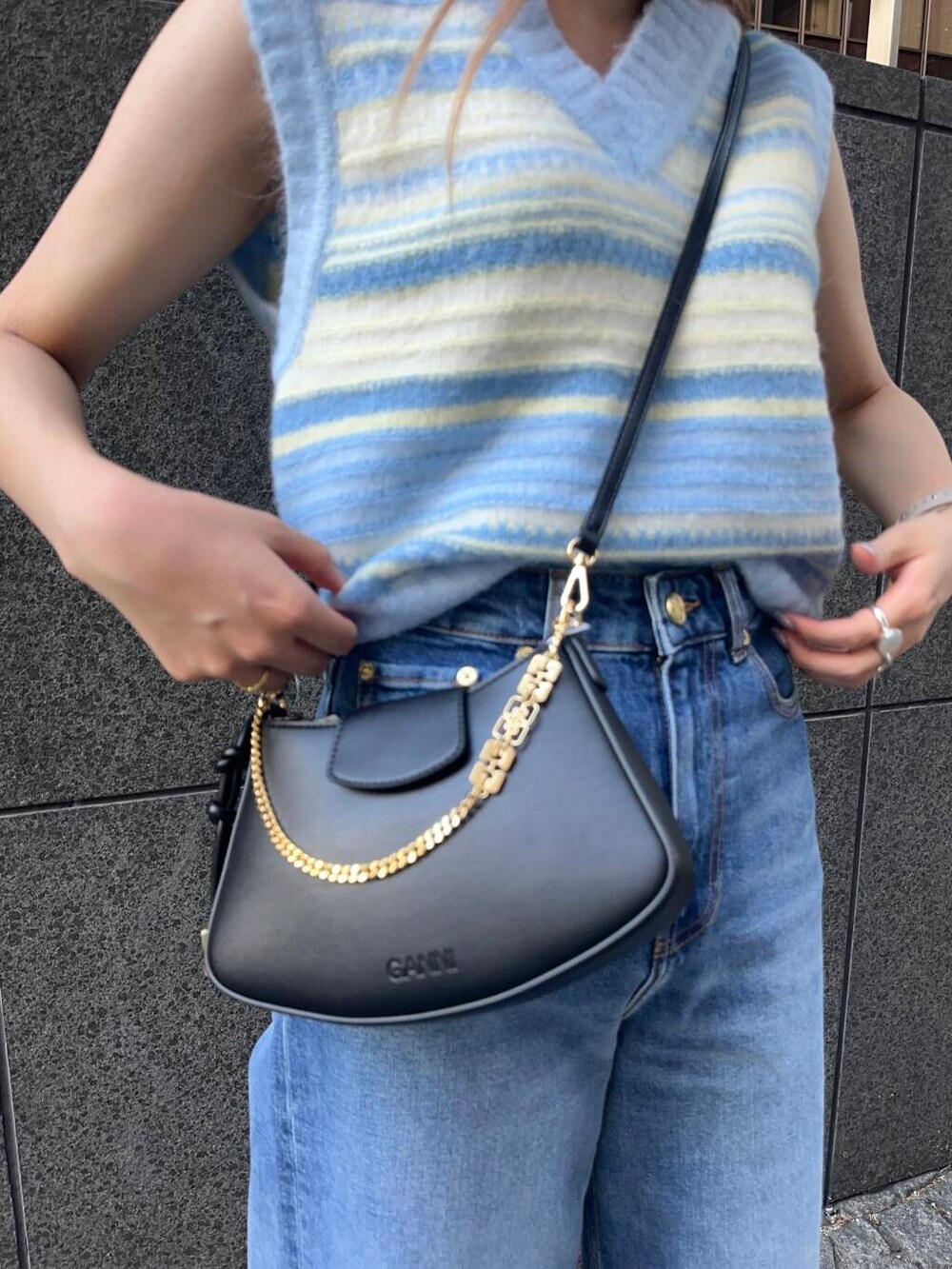 ベージュ系のサンダル、ブルー系のベスト、ブラック系のハンドバッグを着用したレディースの夏コーディネートの3枚目の写真