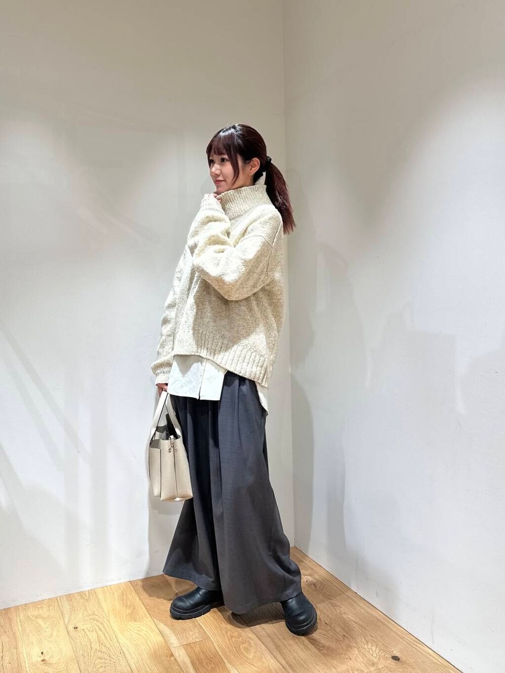 グレー系のその他パンツ、ホワイト系のニット/セーター、ホワイト系のトートバッグを着用したレディースの冬コーディネートの2枚目の写真