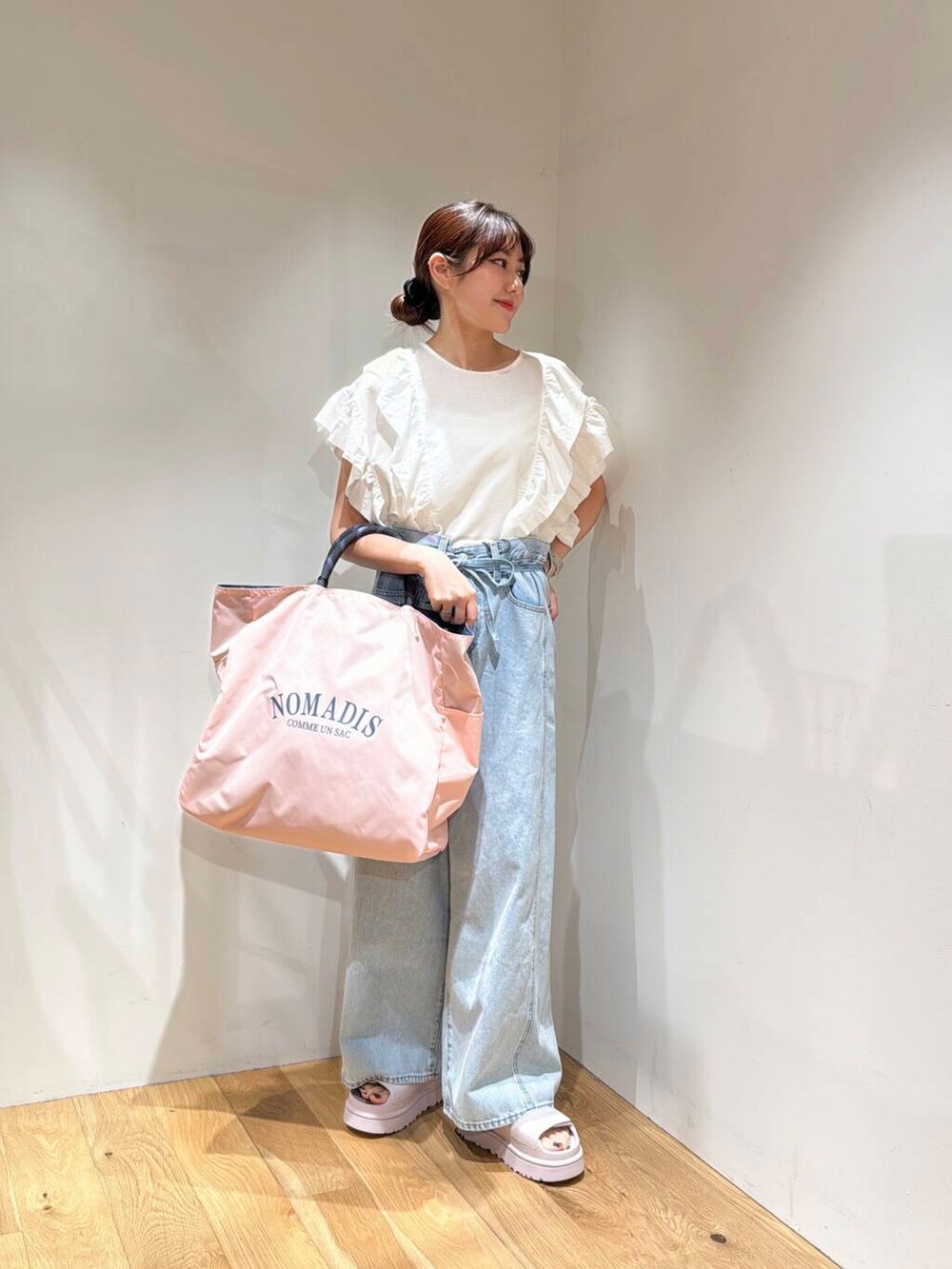 ブルー系のデニムパンツ、ピンク系のトートバッグ、ピンク系のサンダルを着用したレディースの春コーディネートの2枚目の写真