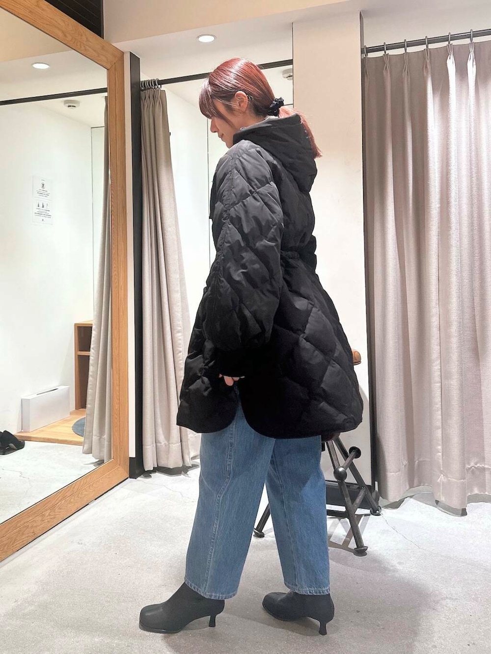 ブルー系のデニムパンツ、ブラック系のブーツ、ブラウン系のショルダーバッグを着用したレディースの冬コーディネートの3枚目の写真