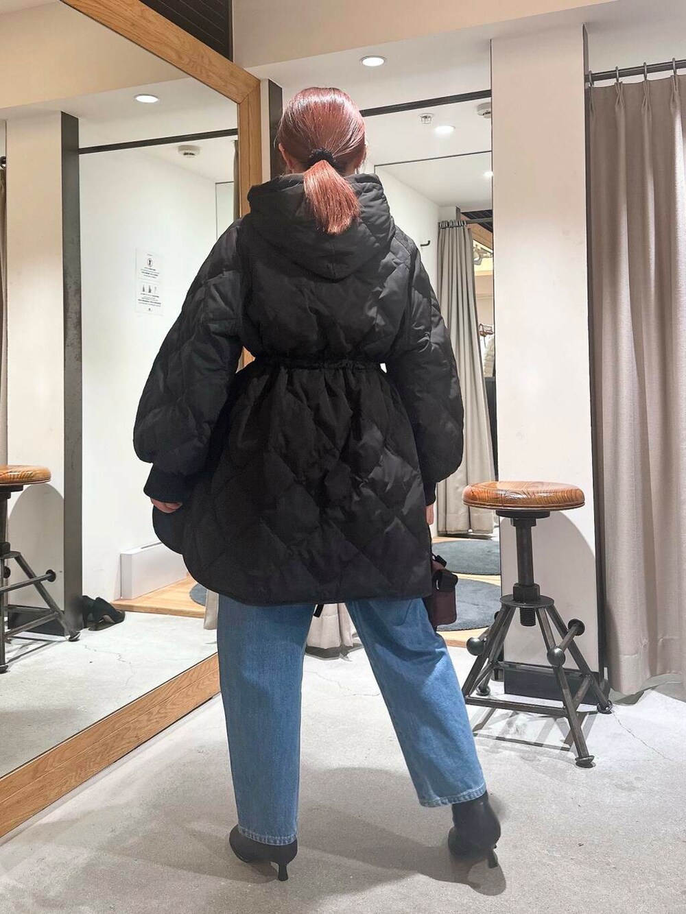 ブルー系のデニムパンツ、ブラック系のブーツ、ブラウン系のショルダーバッグを着用したレディースの冬コーディネートの4枚目の写真