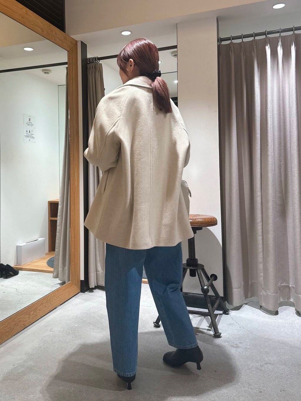 ブルー系のデニムパンツ、ベージュ系のピーコート、ブラック系のブーツを着用したレディースの冬コーディネートの4枚目の写真