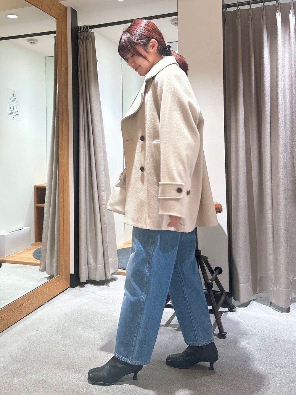 ブルー系のデニムパンツ、ベージュ系のピーコート、ブラック系のブーツを着用したレディースの冬コーディネートの3枚目の写真