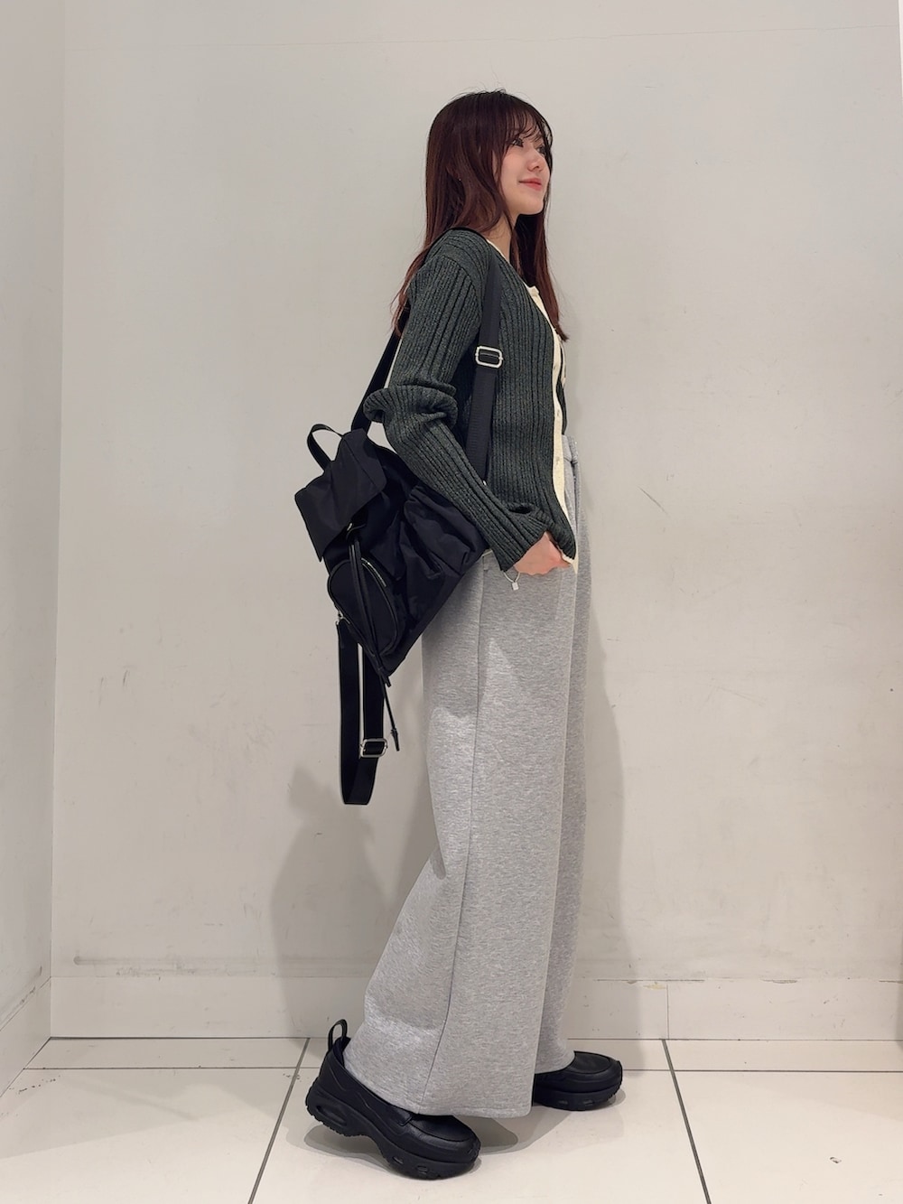 グレー系のニット/セーター、グレー系のその他パンツ、ブラック系のバックパック/リュックを着用したレディースの春コーディネートの3枚目の写真