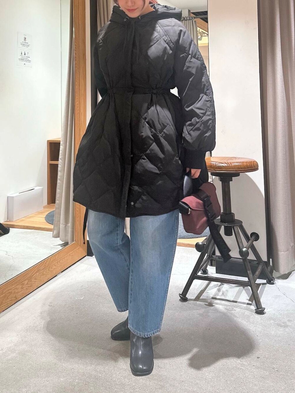 ブルー系のデニムパンツ、ブラック系のブーツ、ブラウン系のショルダーバッグを着用したレディースの冬コーディネートの2枚目の写真