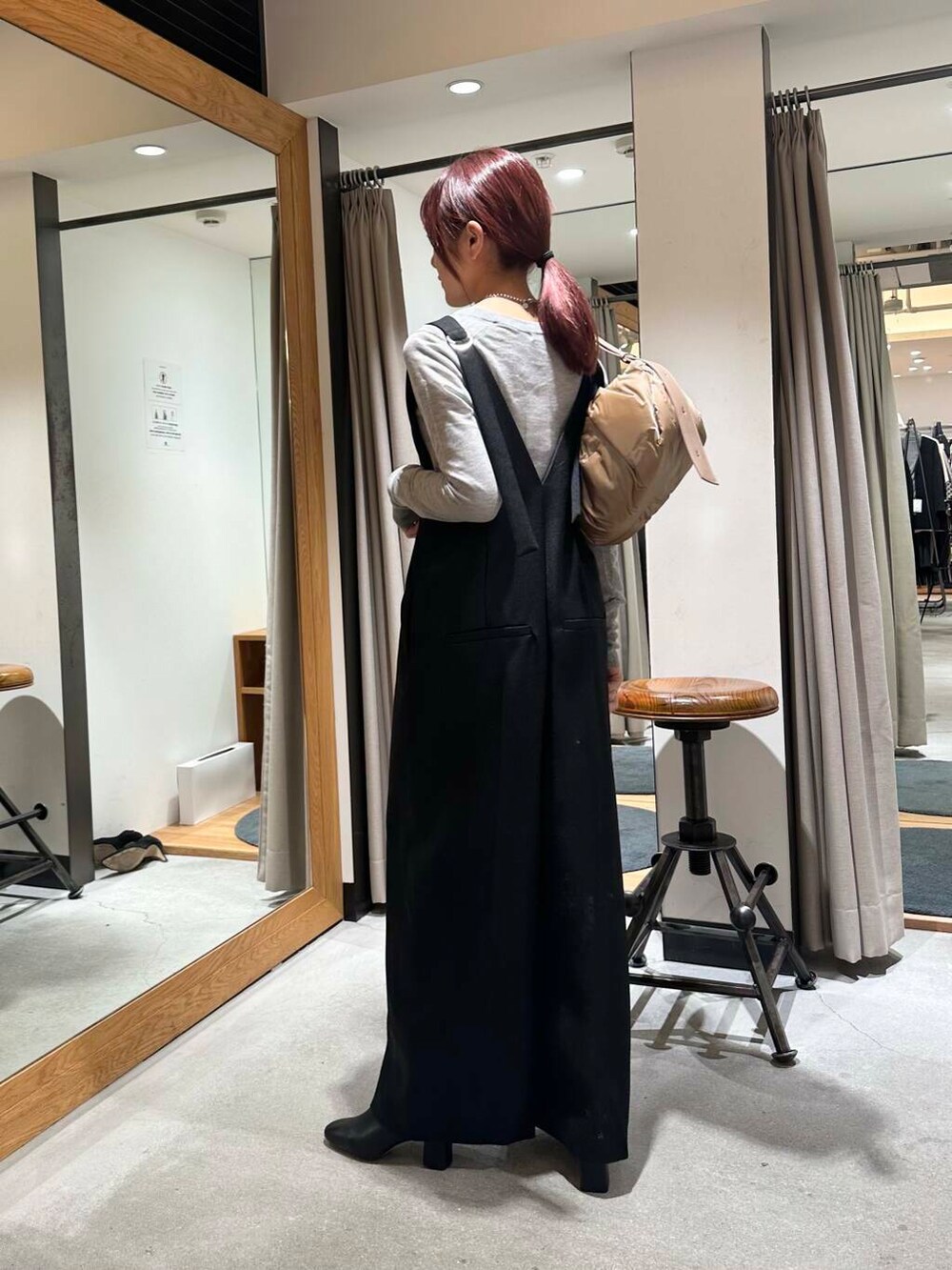 グレー系のニット/セーター、ブラック系のサロペット/オーバーオール、ベージュ系のショルダーバッグを着用したレディースの冬コーディネートの2枚目の写真