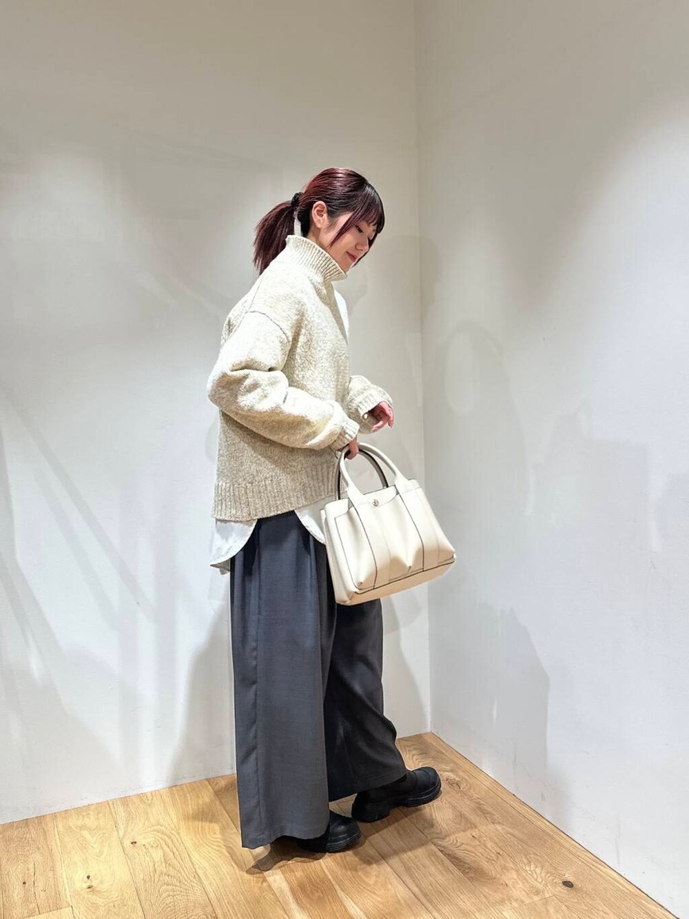 グレー系のその他パンツ、ホワイト系のニット/セーター、ホワイト系のトートバッグを着用したレディースの冬コーディネートの3枚目の写真