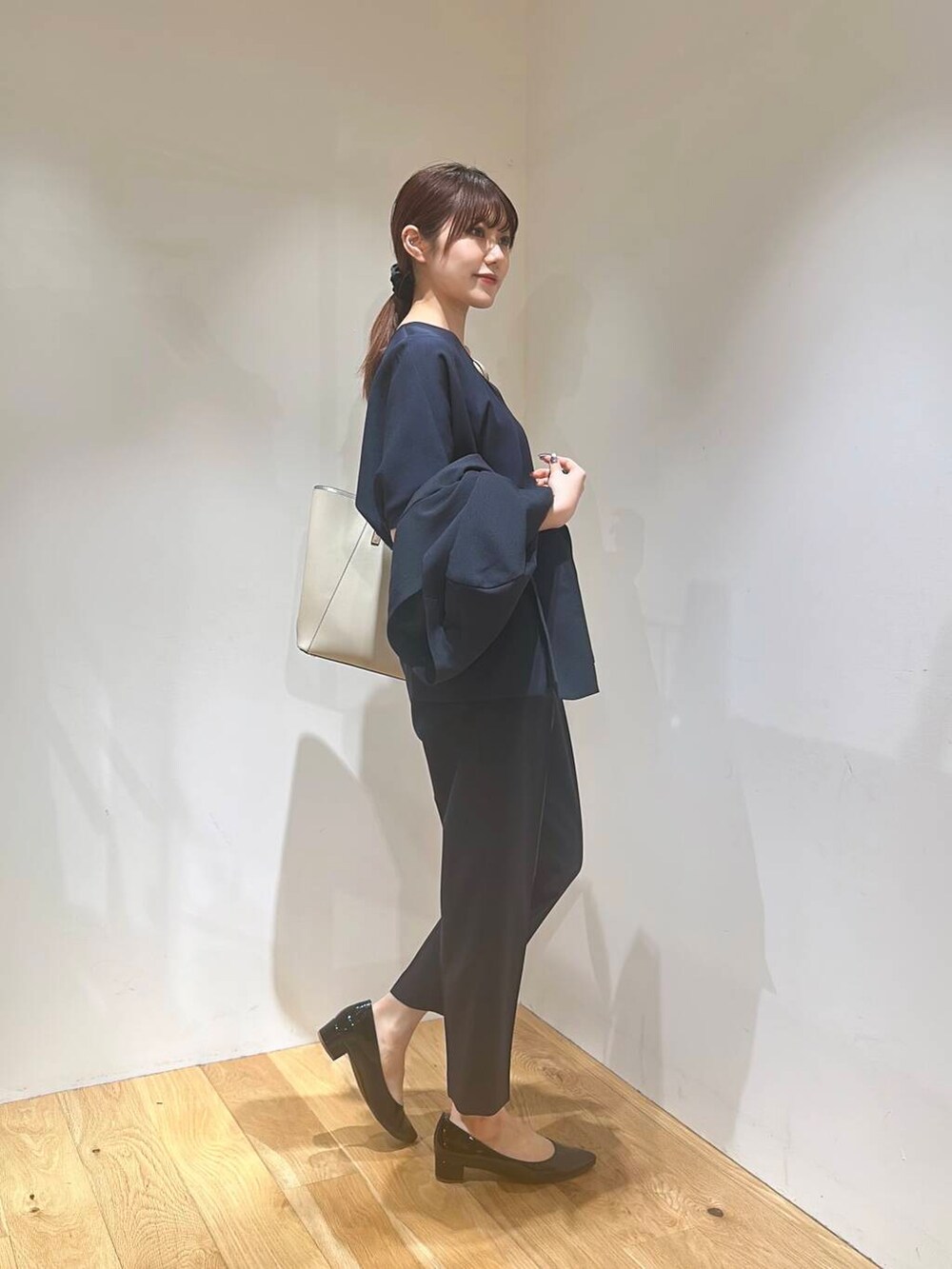 ホワイト系のトートバッグ、ブラック系のパンプス、ブルー系のその他パンツを着用したレディースの春コーディネートの3枚目の写真