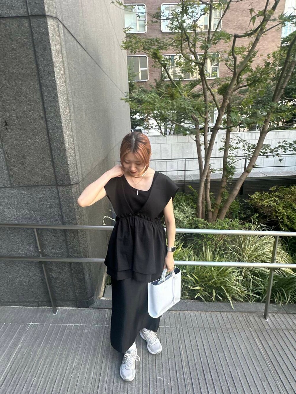 ホワイト系のトートバッグ、ブラック系のベスト、ブラック系のタンクトップを着用したレディースの夏コーディネートの3枚目の写真