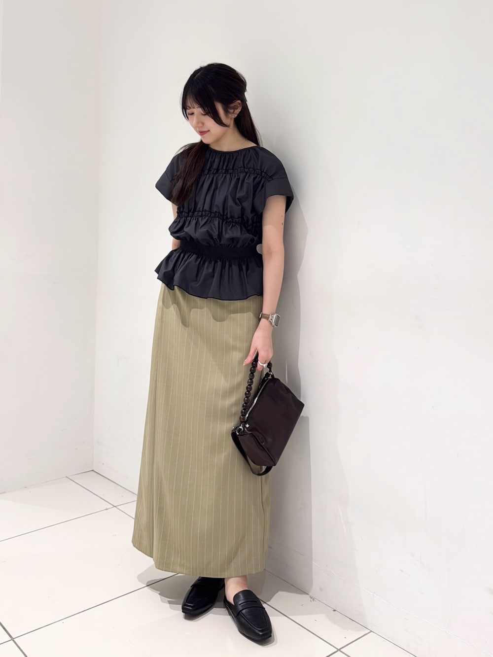 グレー系のシャツ/ブラウス、ベージュ系のスカート、ブラウン系のショルダーバッグを着用したレディースの夏コーディネートの2枚目の写真