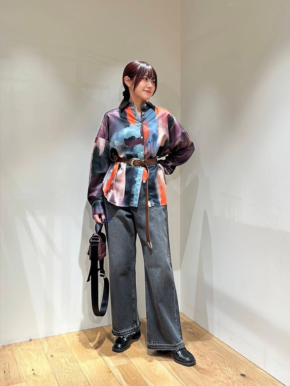 ブラック系のデニムパンツ、ブラウン系のショルダーバッグ、ピンク系のシャツ/ブラウスを着用したレディースの冬コーディネートの2枚目の写真