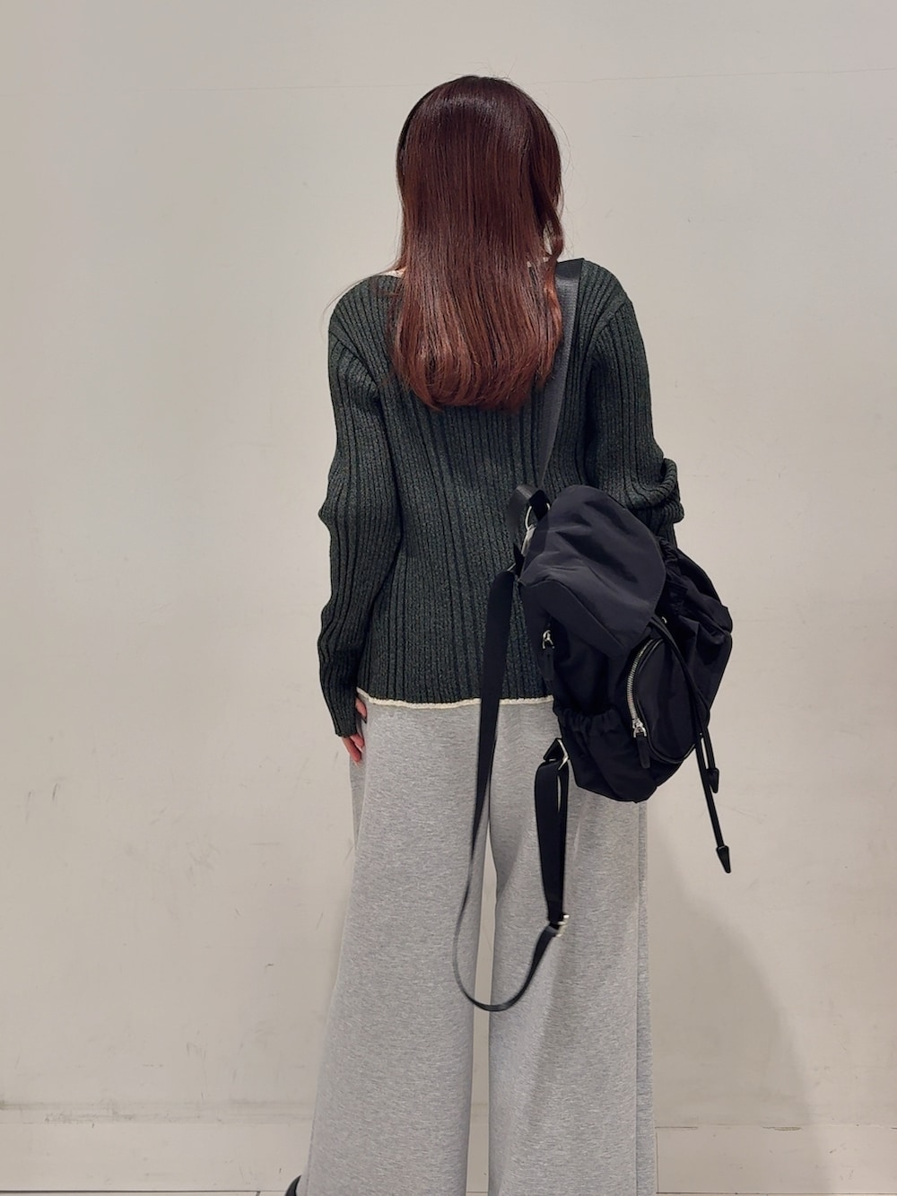 グレー系のニット/セーター、グレー系のその他パンツ、ブラック系のバックパック/リュックを着用したレディースの春コーディネートの4枚目の写真