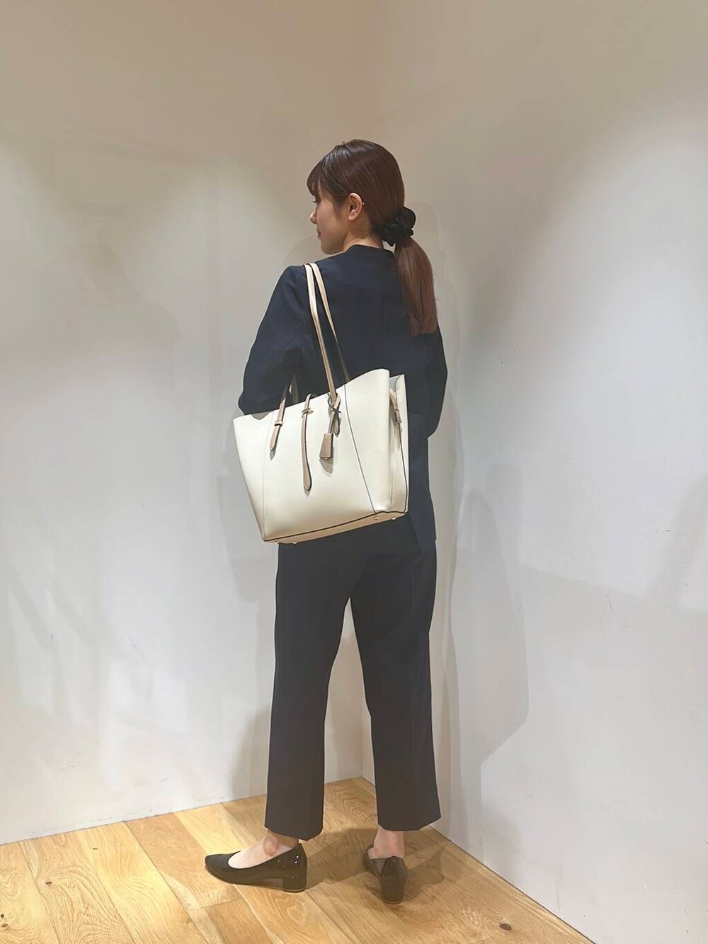 ホワイト系のトートバッグ、ブラック系のパンプス、ブルー系のその他パンツを着用したレディースの春コーディネートの4枚目の写真