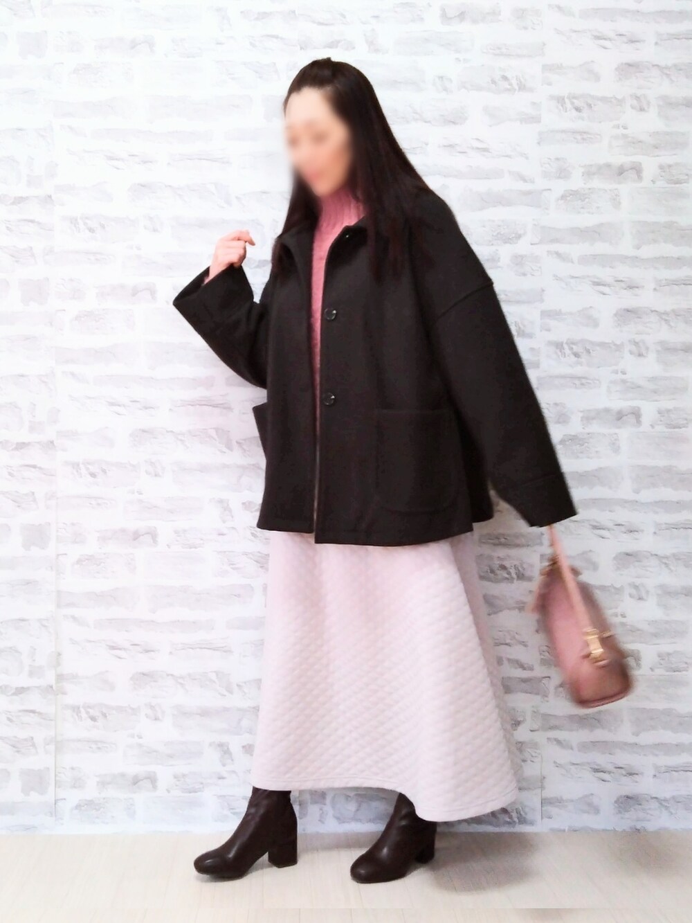 ピンク系のニット/セーター、ブラック系のジャケット/アウター、ホワイト系のスカートを着用したレディースの冬コーディネートの2枚目の写真