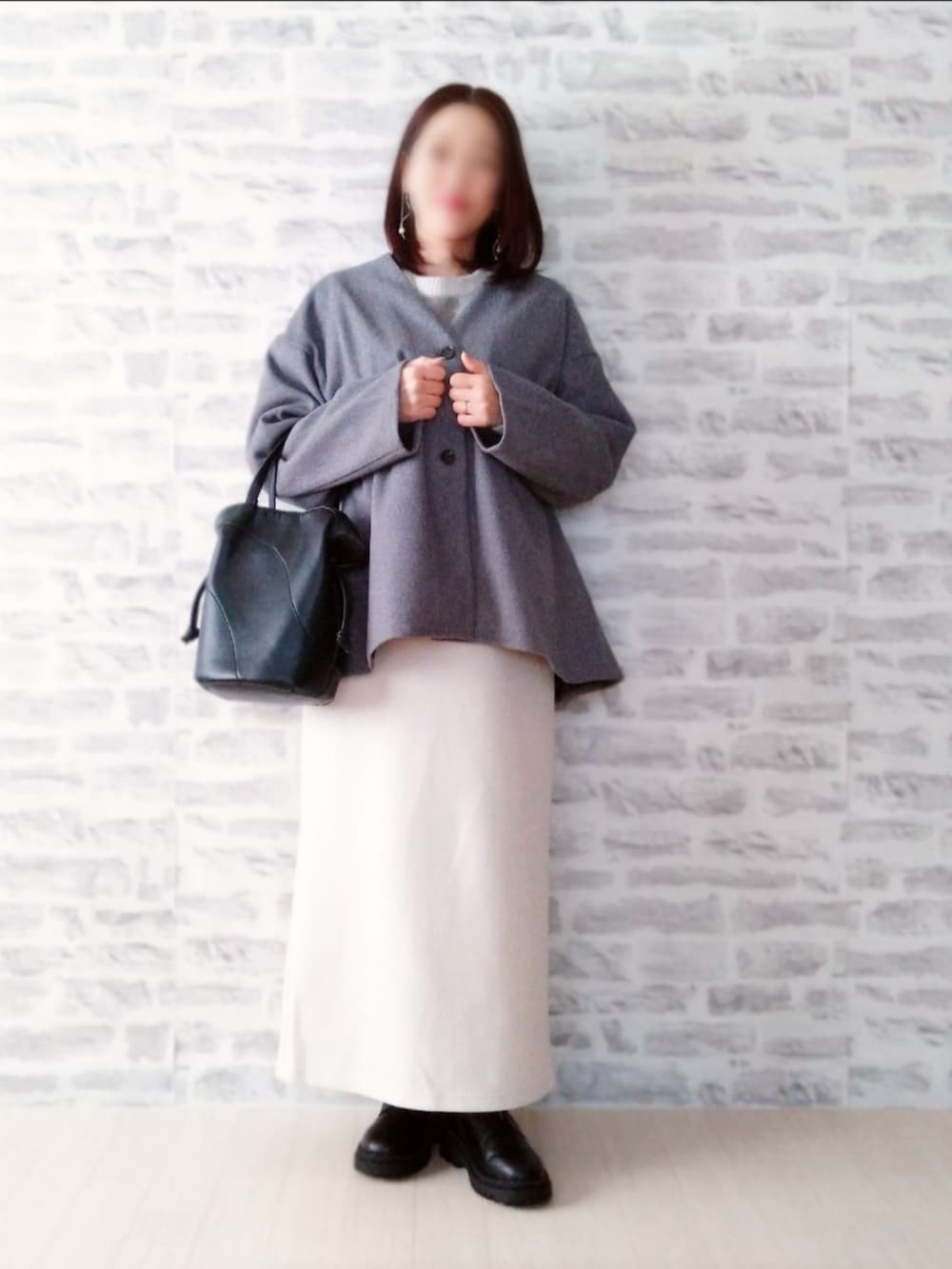 グレー系のニット/セーター、ホワイト系のジャンパースカート、ブラック系のバッグを着用したレディースの冬コーディネートの2枚目の写真