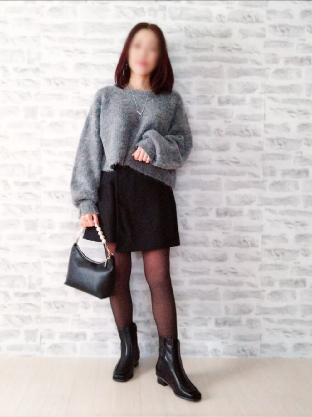 ブラック系のダウンジャケット/コート、グレー系のニット/セーター、ブラック系のスカートを着用したレディースの秋コーディネートの2枚目の写真