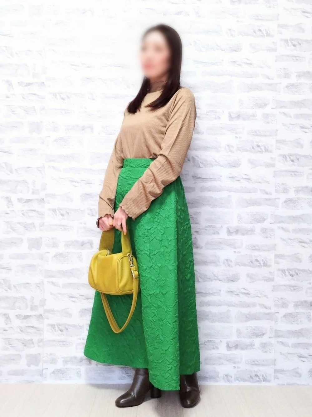 ベージュ系のトップス、グレー系のノーカラーコート、グリーン系のスカートを着用したレディースの冬コーディネートの2枚目の写真