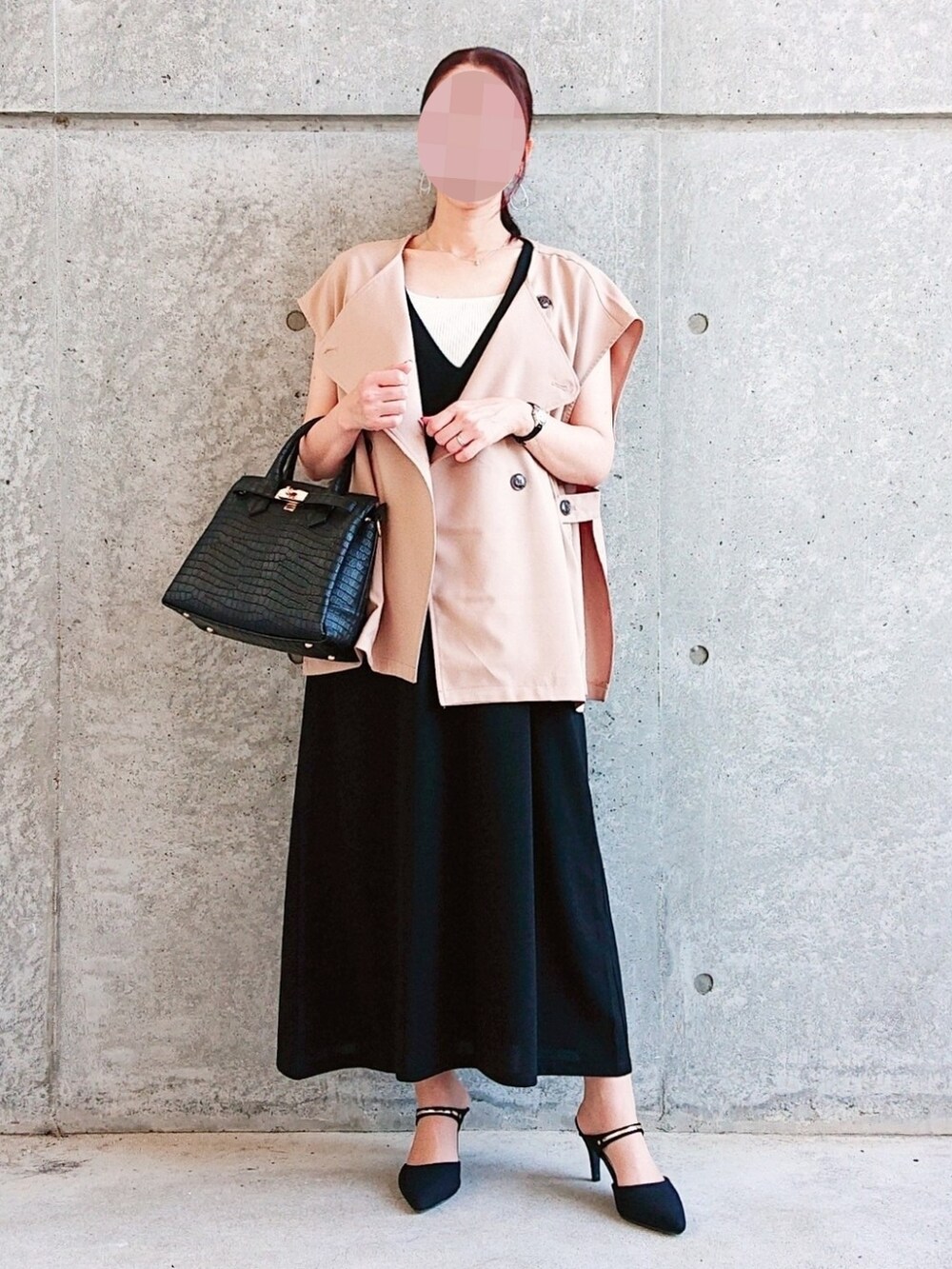 ベージュ系のベスト、ホワイト系のタンクトップ、ブラック系のジャンパースカートを着用したレディースの秋コーディネートの2枚目の写真