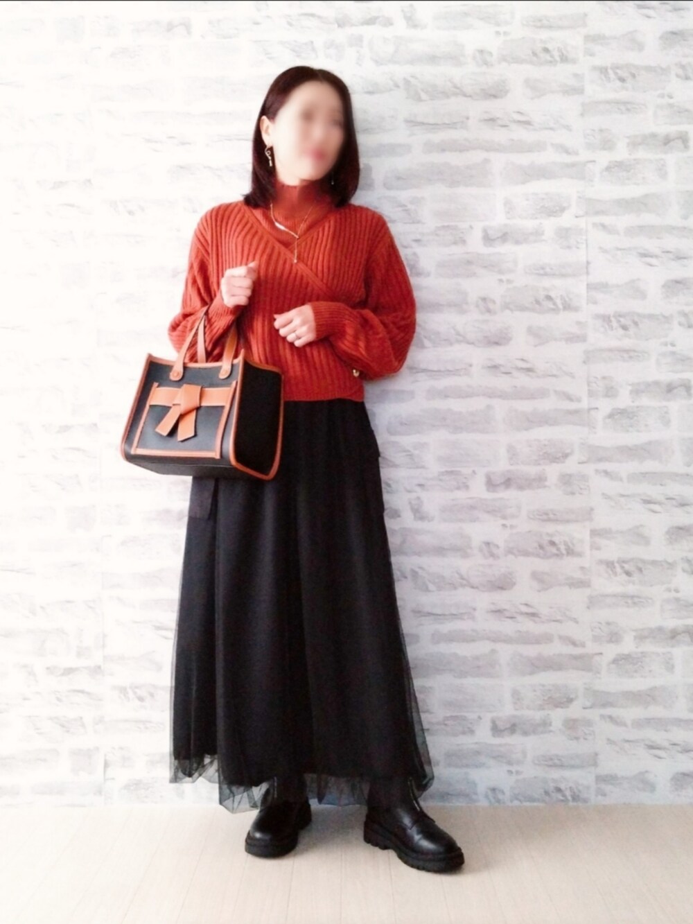 オレンジ系のトップス、ブラック系のスカート、ブラック系のトートバッグを着用したレディースの冬コーディネートの2枚目の写真
