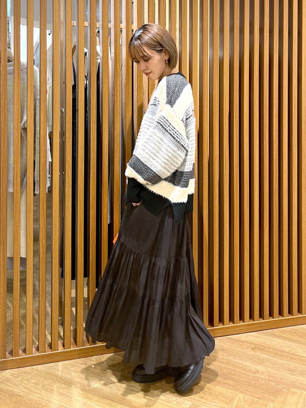 オレンジ系のショルダーバッグ、ブラック系のスカート、ブラック系のニット/セーターを着用したレディースの秋コーディネートの4枚目の写真