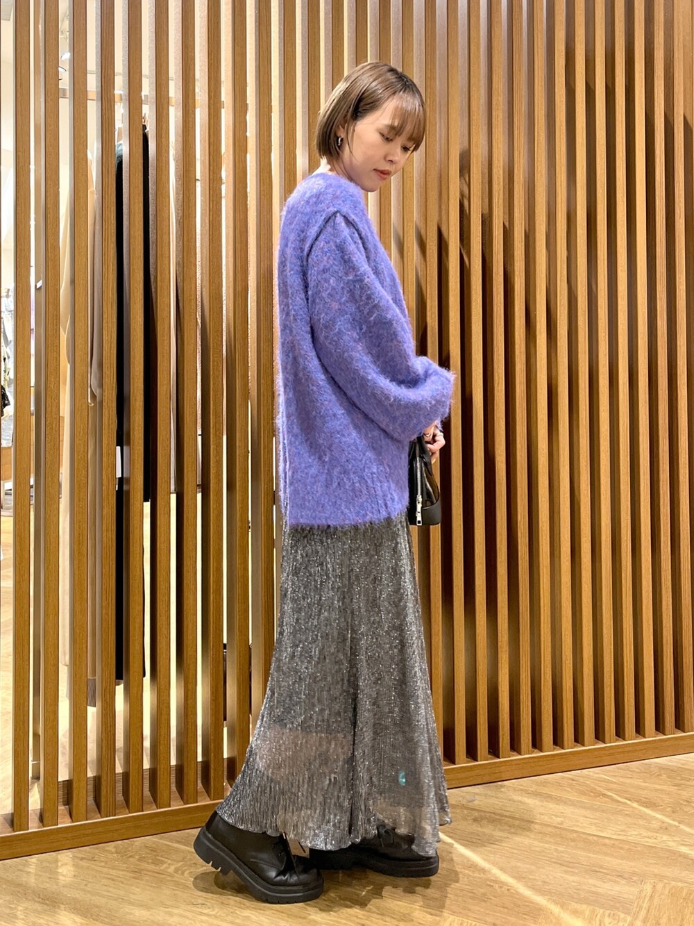 ブルー系のニット/セーター、ブラック系のスカート、ブラック系のブーツを着用したレディースの秋コーディネートの2枚目の写真