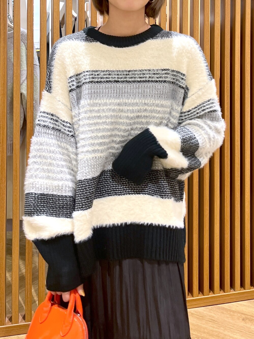 オレンジ系のショルダーバッグ、ブラック系のスカート、ブラック系のニット/セーターを着用したレディースの秋コーディネートの6枚目の写真