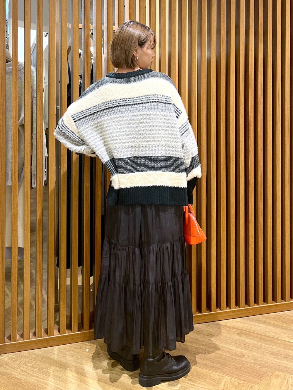 オレンジ系のショルダーバッグ、ブラック系のスカート、ブラック系のニット/セーターを着用したレディースの秋コーディネートの5枚目の写真