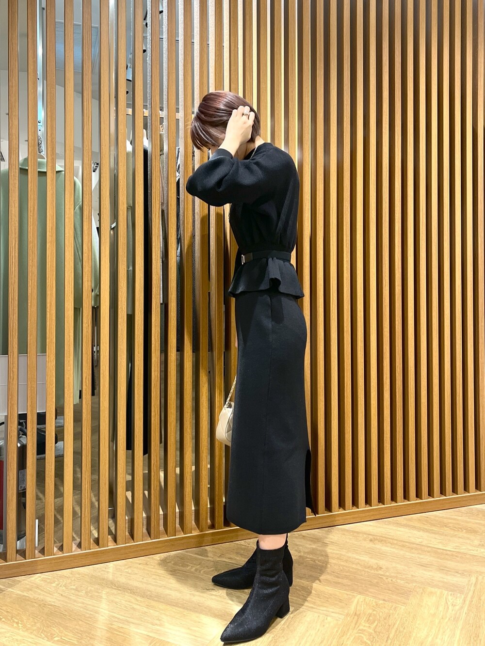 ブラック系のワンピース、ベージュ系のショルダーバッグ、ブラック系のブーツを着用したレディースの秋コーディネートの2枚目の写真