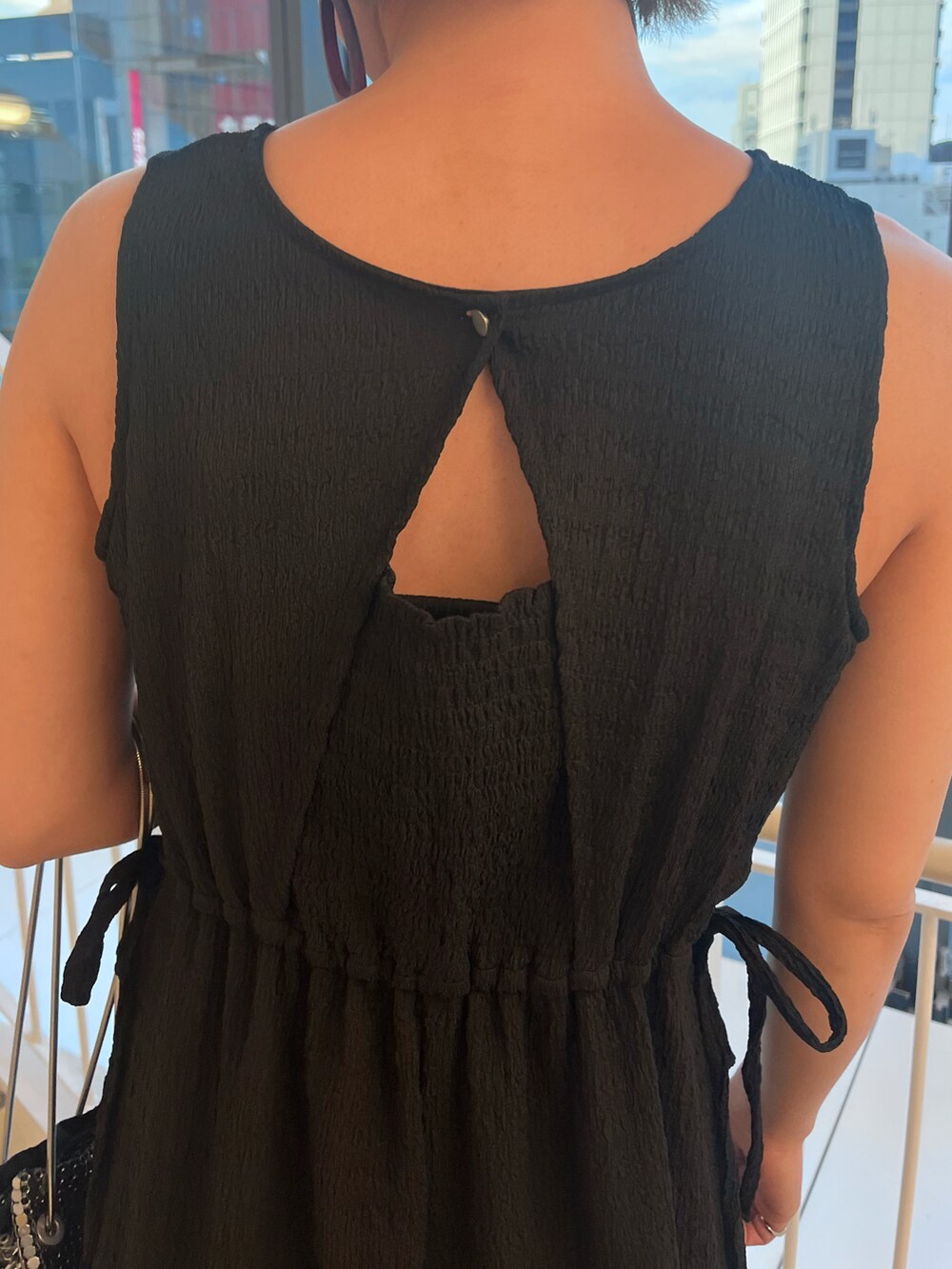 ブラック系のワンピース、シルバー系のショルダーバッグを着用したレディースの夏コーディネートの3枚目の写真