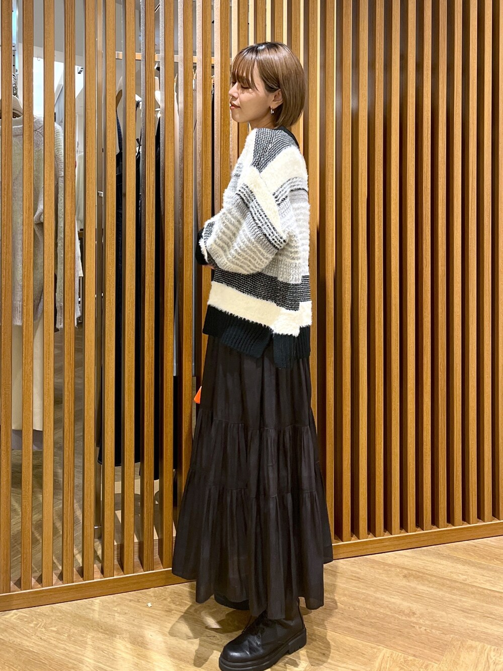 オレンジ系のショルダーバッグ、ブラック系のスカート、ブラック系のニット/セーターを着用したレディースの秋コーディネートの3枚目の写真