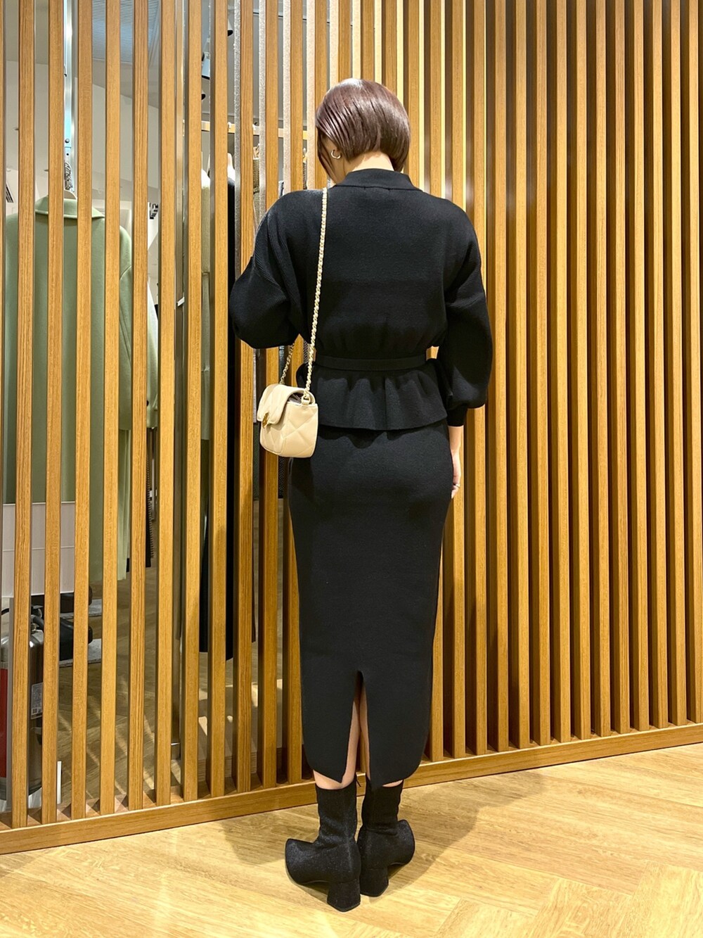 ブラック系のワンピース、ベージュ系のショルダーバッグ、ブラック系のブーツを着用したレディースの秋コーディネートの3枚目の写真