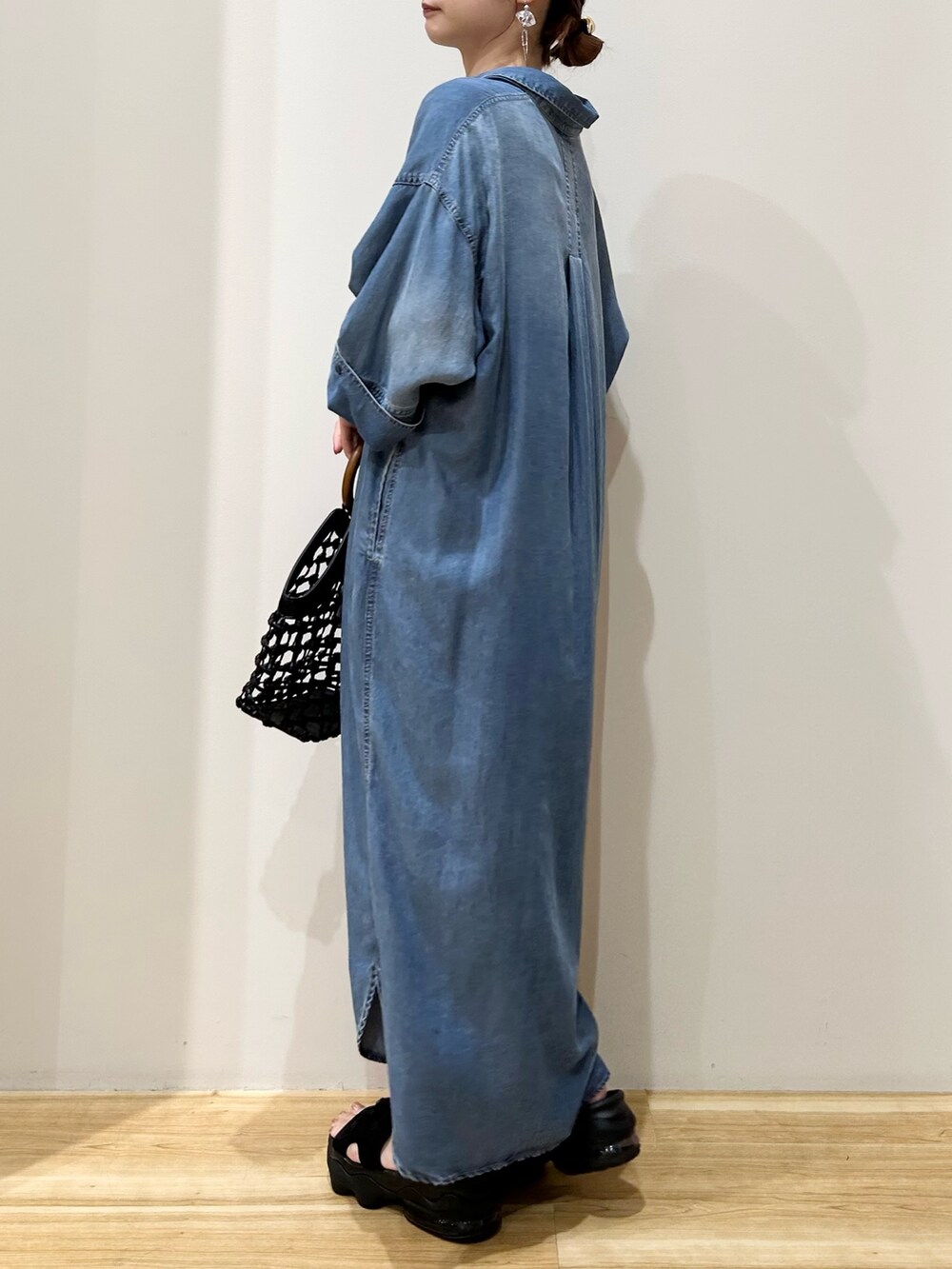 ブラック系のサンダル、ブラック系のハンドバッグ、ブルー系のワンピースを着用したレディースの夏コーディネートの2枚目の写真