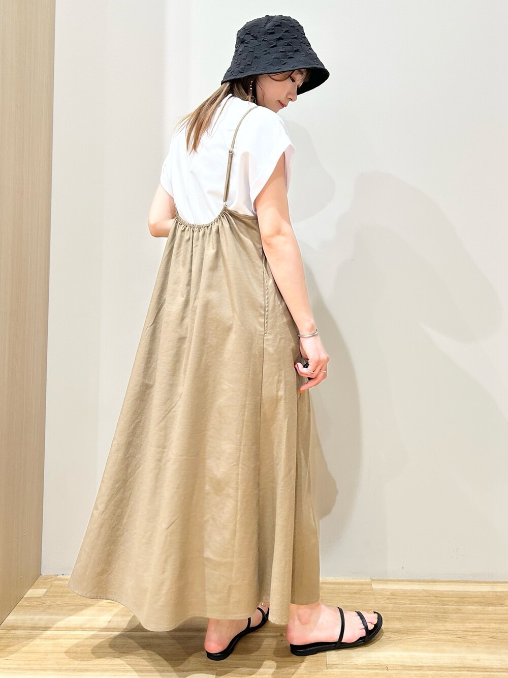 ホワイト系のTシャツ/カットソー、ベージュ系のワンピース、ブラック系のサンダルを着用したレディースの夏コーディネートの2枚目の写真