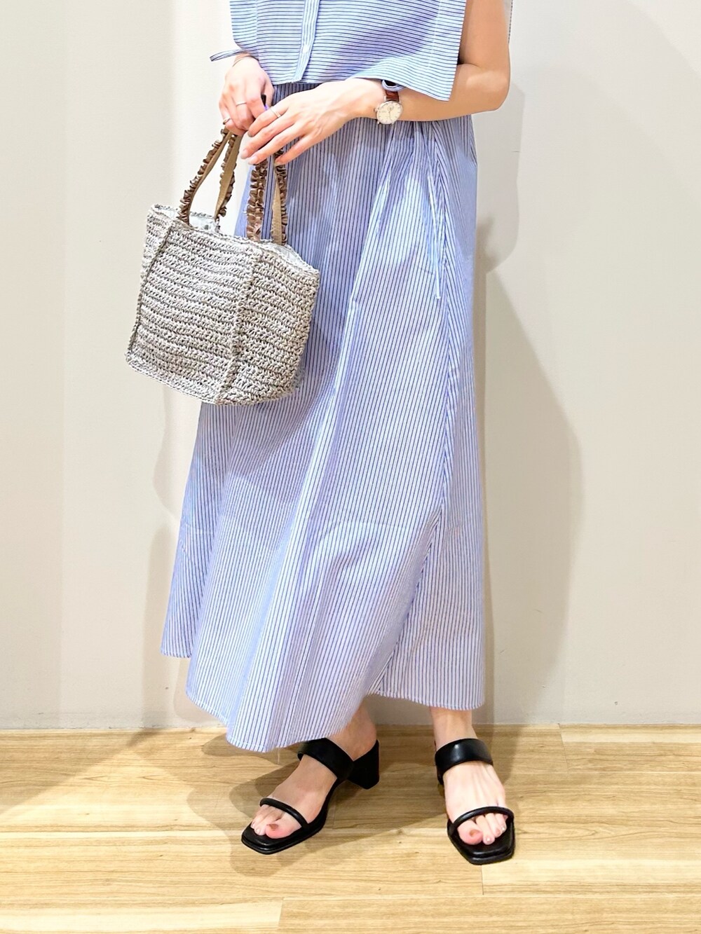 グレー系のかごバッグ、ブラック系のサンダル、ブルー系のワンピースを着用したレディースの夏コーディネートの3枚目の写真