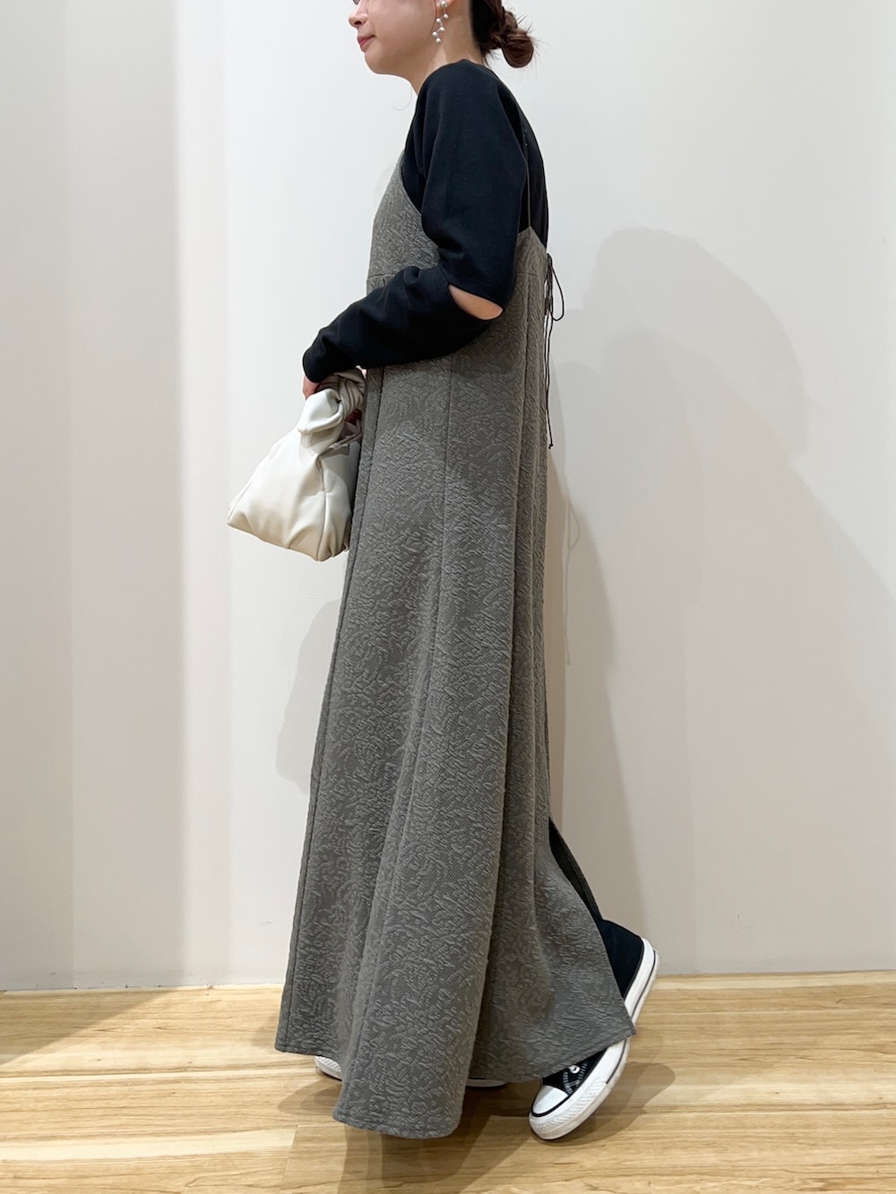 ブラック系のスニーカー、ブラック系のTシャツ/カットソー、ホワイト系のハンドバッグを着用したレディースの春コーディネートの2枚目の写真