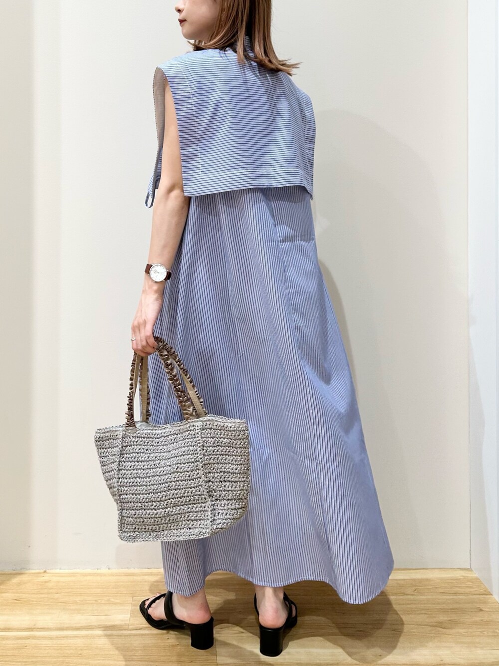 グレー系のかごバッグ、ブラック系のサンダル、ブルー系のワンピースを着用したレディースの夏コーディネートの2枚目の写真