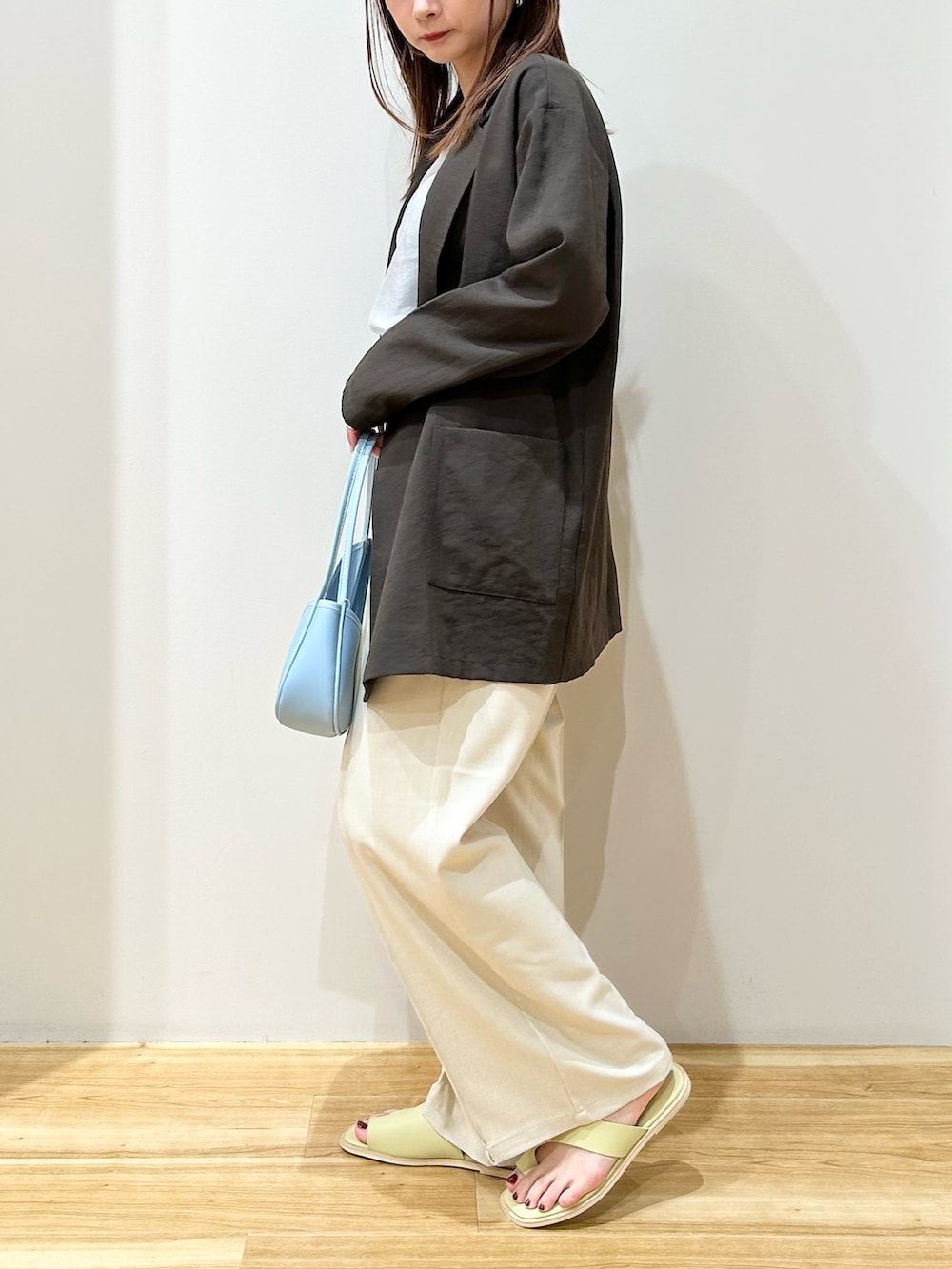 ブラウン系のテーラードジャケット、ブルー系のハンドバッグ、グリーン系のサンダルを着用したレディースの春コーディネートの2枚目の写真