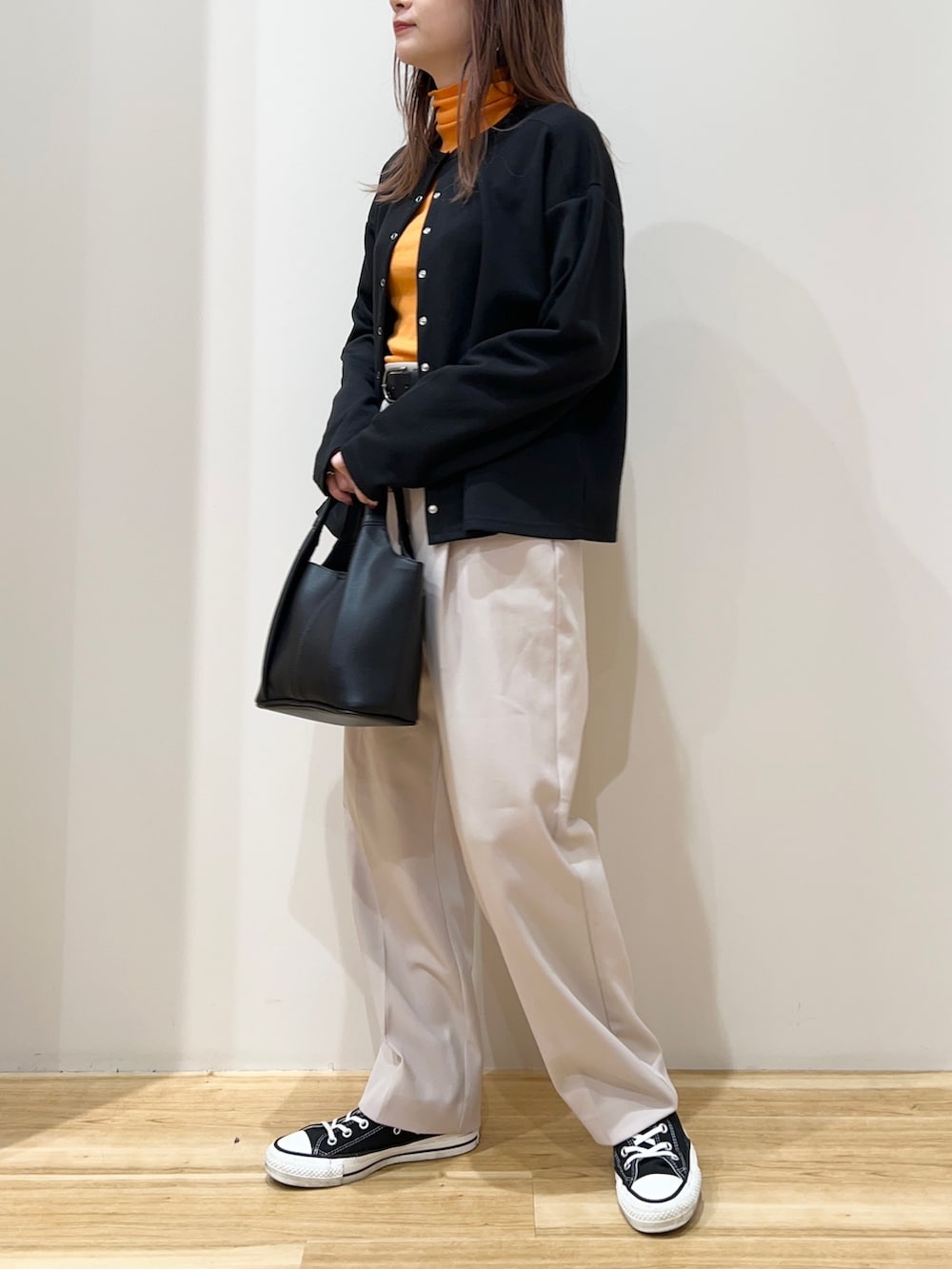 ブラック系のカーディガン/ボレロ、オレンジ系のTシャツ/カットソー、ベージュ系のその他パンツを着用したレディースの春コーディネートの2枚目の写真