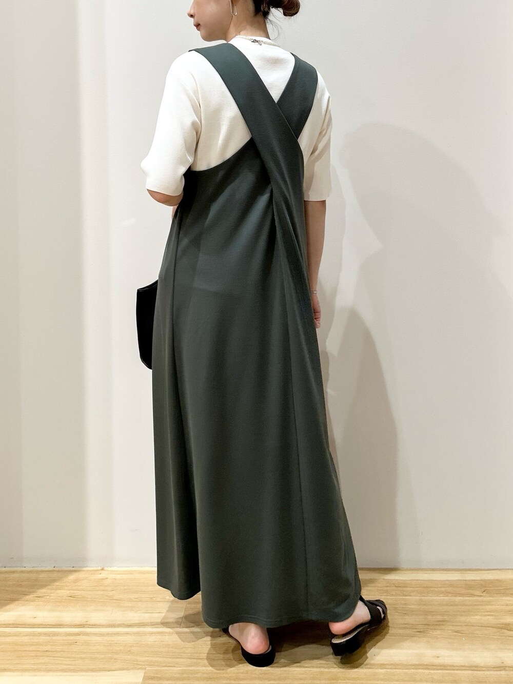 ホワイト系のニット/セーター、グリーン系のジャンパースカート、ブラック系のトートバッグを着用したレディースの春コーディネートの3枚目の写真